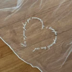 Voile de mariée personnalisé, brodé à la main d'une phrase en forme de cœur sur tulle.
