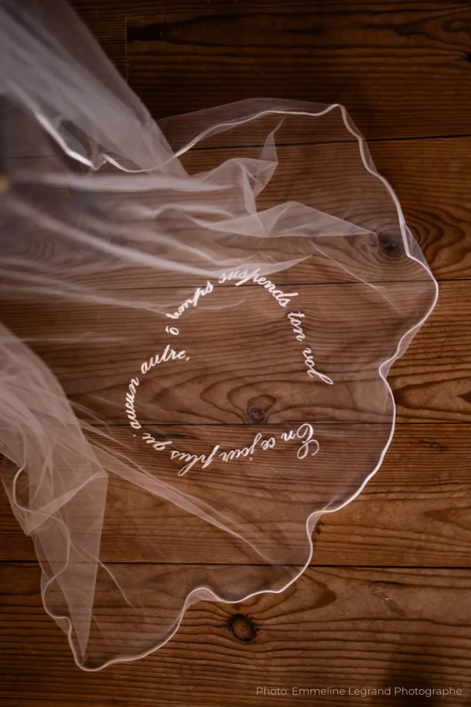 Voile de mariée personnalisé Celestia déployé sur un parquet, mettant en valeur sa délicate broderie en forme de cœur.