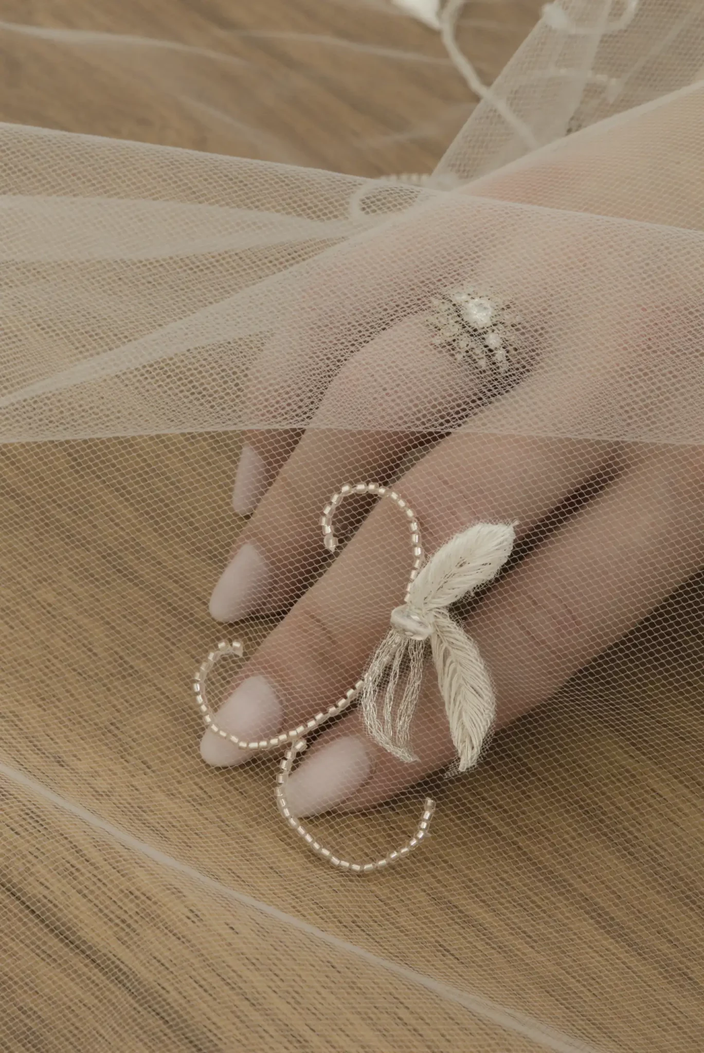 Detalle macro de un bordado de novia personalizado con una delicada enredadera y tres hojas de olivo bordadas en relieve.