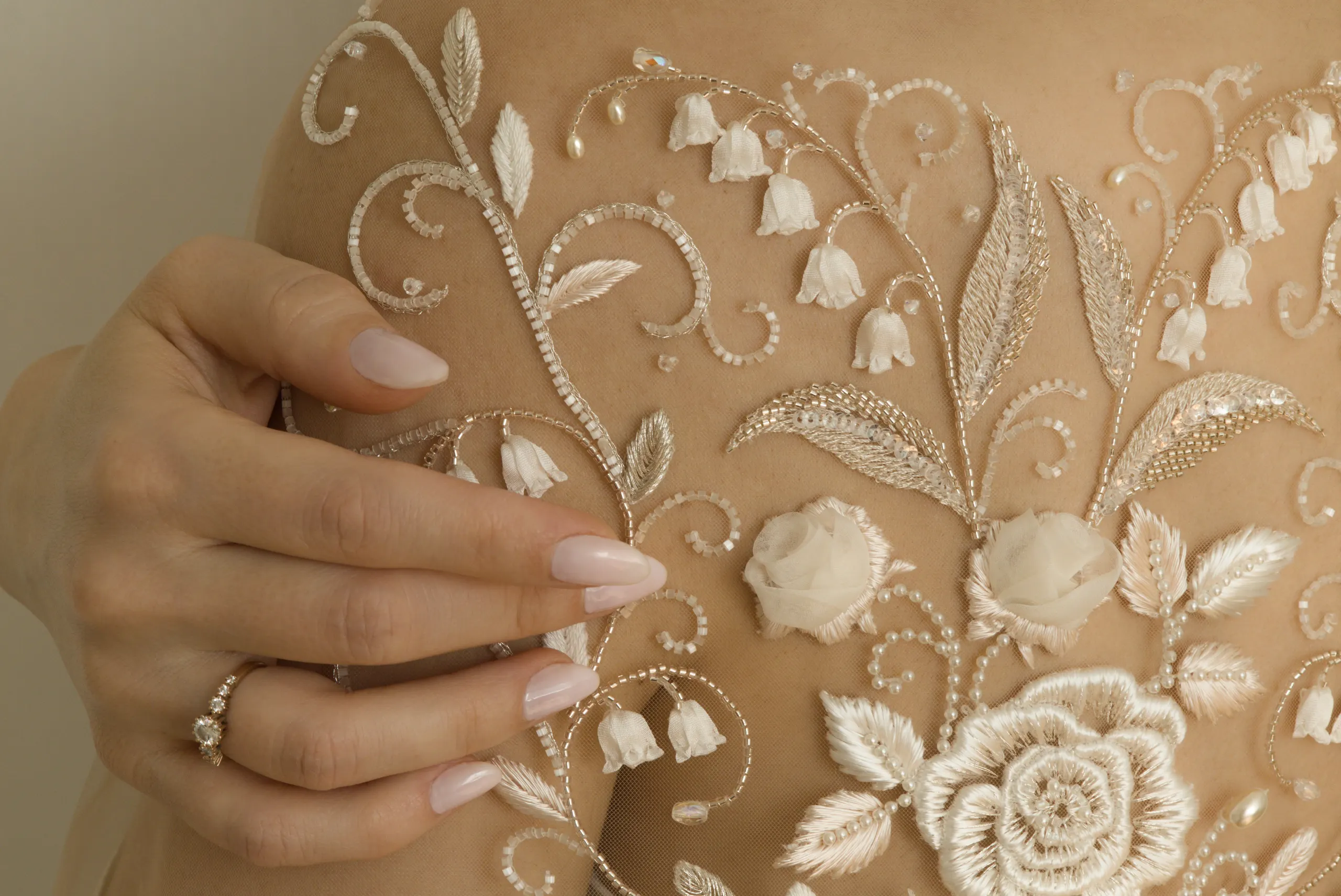 Bordado de novia personalizado sobre tul transparente, creando un delicado efecto tatuaje sobre la piel, con una alianza junto al bordado.