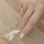 Broderie de mariée sur mesure sur un voile de mariée cathédrale, photographiée sur la main d’une mariée portant une alliance.