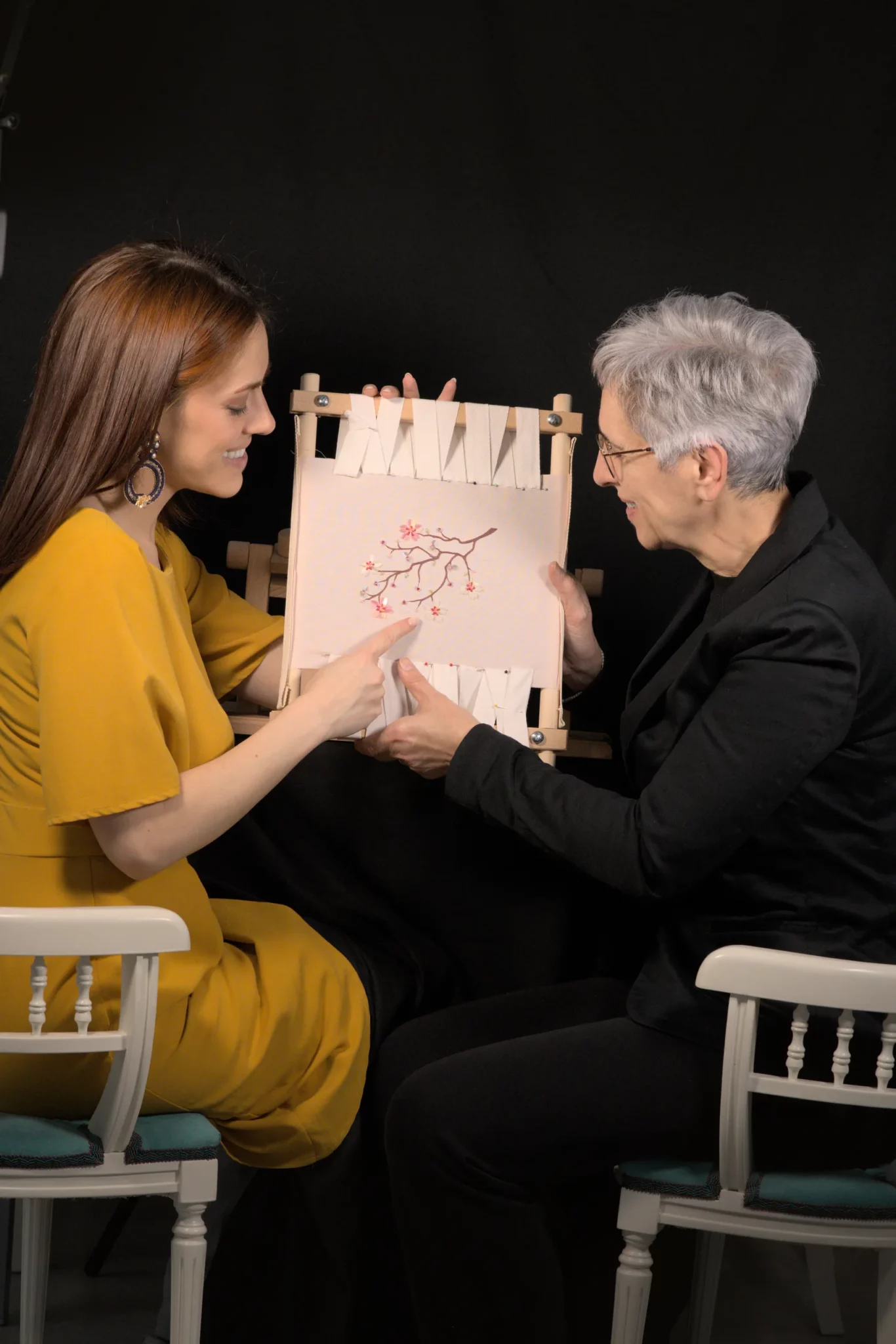 Embroidery teacher Laura S. Urbina demonstrating Luneville hook techniques to a student during a hands-on Haute Couture embroidery workshop.