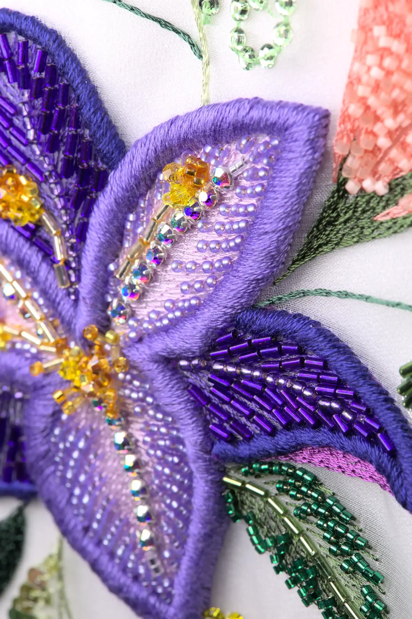 Macro detail of a violet lily in bespoke haute couture embroidery, highlighting rich textures, carefully selected materials and exquisite finishing.
